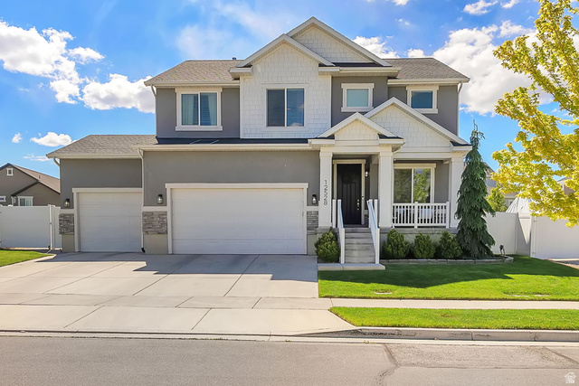 Undisclosed Address Herriman, UT 84096 - Photo 1 of 1 Contemporary two-story residence featuring a covered front porch with white railing, a three-car garage, and a concrete driveway