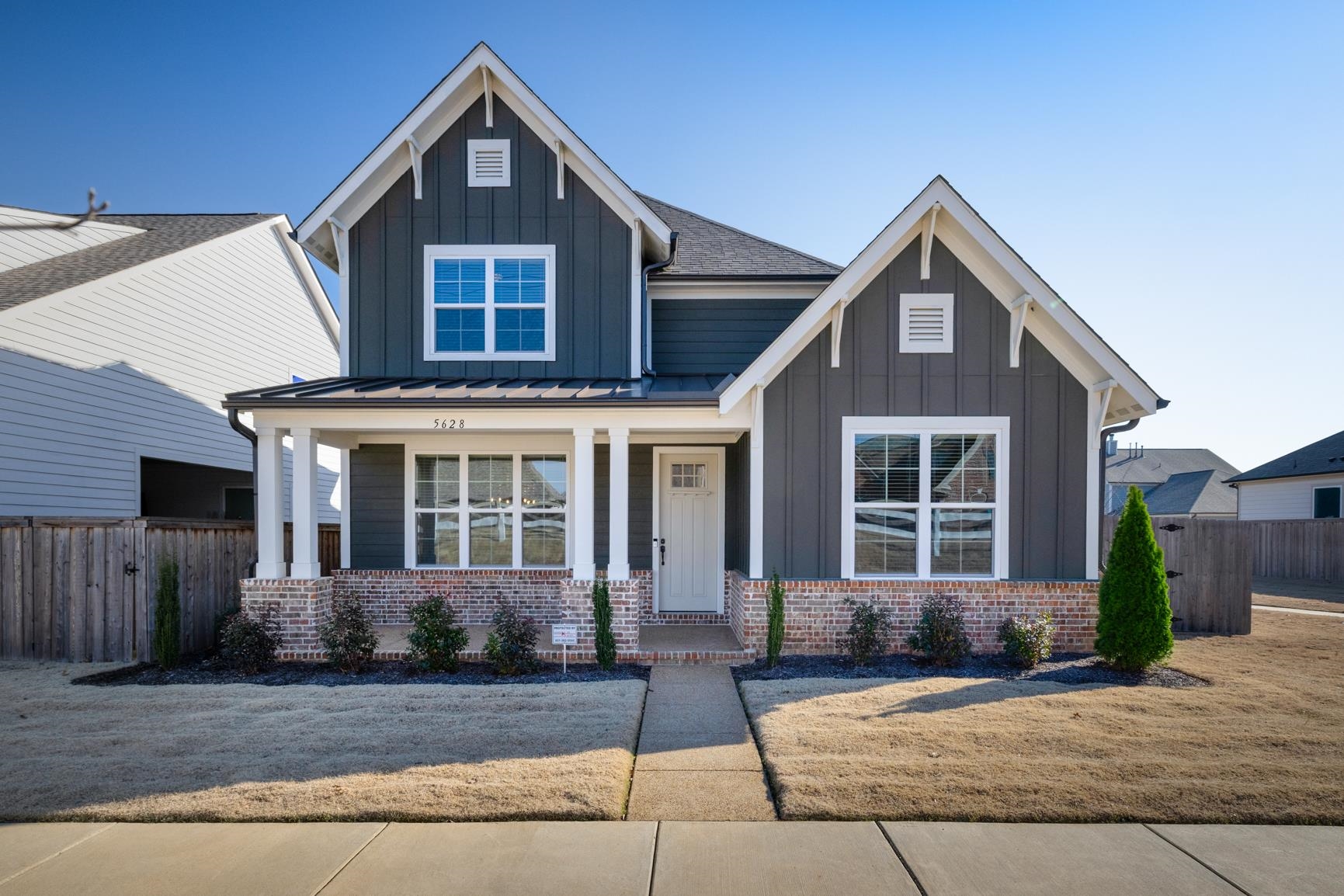 Craftsman inspired home featuring board and batten siding, a porch, and brick siding