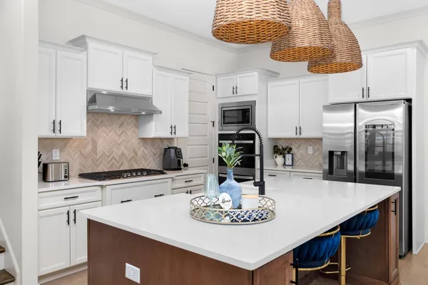 a kitchen with stainless steel appliances granite countertop a sink a stove a refrigerator a dining table and chairs with wooden floor