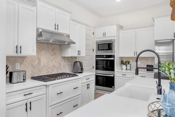 a kitchen with stainless steel appliances kitchen island granite countertop a stove a sink and a white cabinets