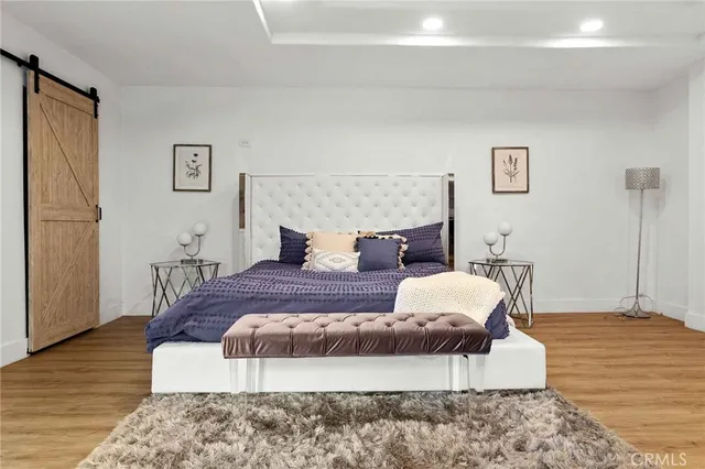 a spacious bedroom with a bed and wooden floor