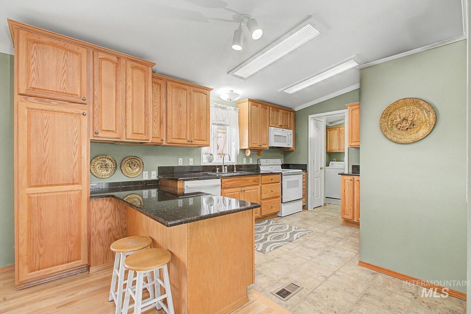 1480 Birch Street Clarkston, WA 99403 - Photo 10 of 30 Kitchen with lofted ceiling, white appliances, dark stone countertops, ornamental molding, and a peninsula