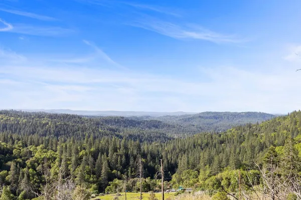a view of a lush green outdoor space with a swimming pool and valleys in the background