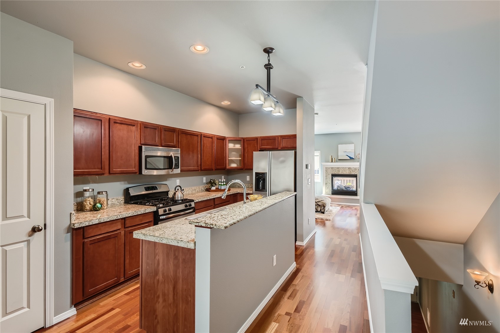 1054 215th Place Southeast Bothell, WA 98021 - Photo 8 of 28 a kitchen with stainless steel appliances a stove top oven a sink a refrigerator white cabinets and wooden floor