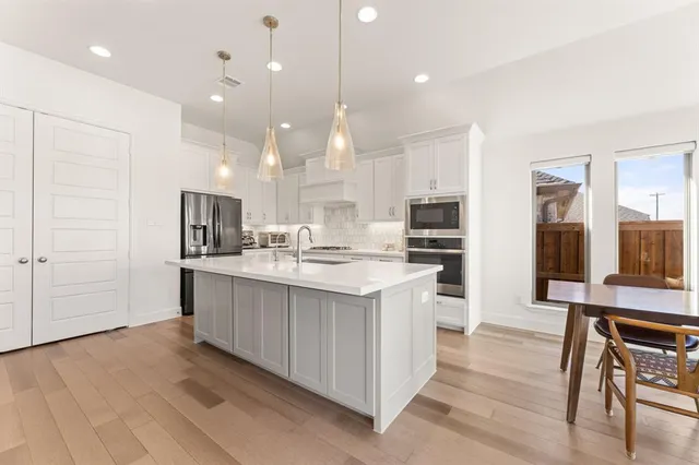 a kitchen with granite countertop a stove a sink a dining table and chairs