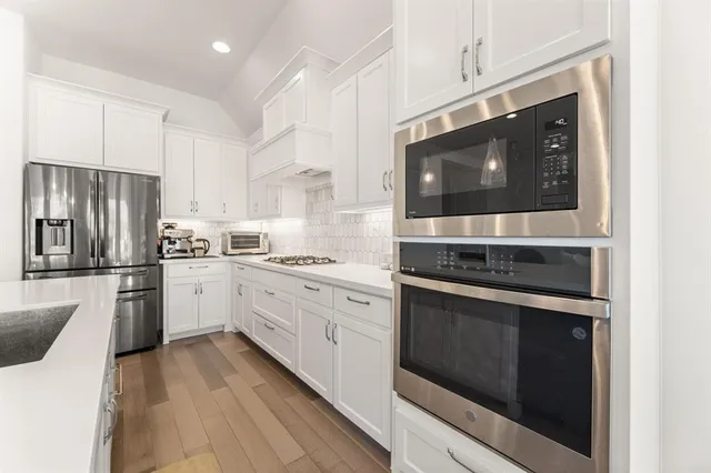 a kitchen with kitchen island granite countertop a sink appliances and cabinets