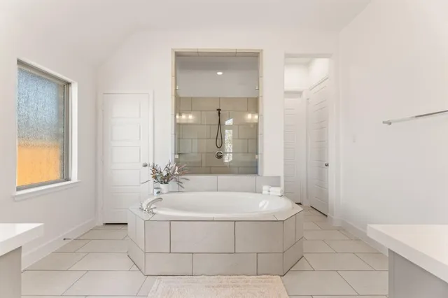 a spacious bathroom with a granite countertop sink mirror and a bathtub