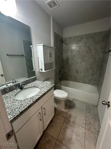 a bathroom with a granite countertop sink a toilet and bathtub