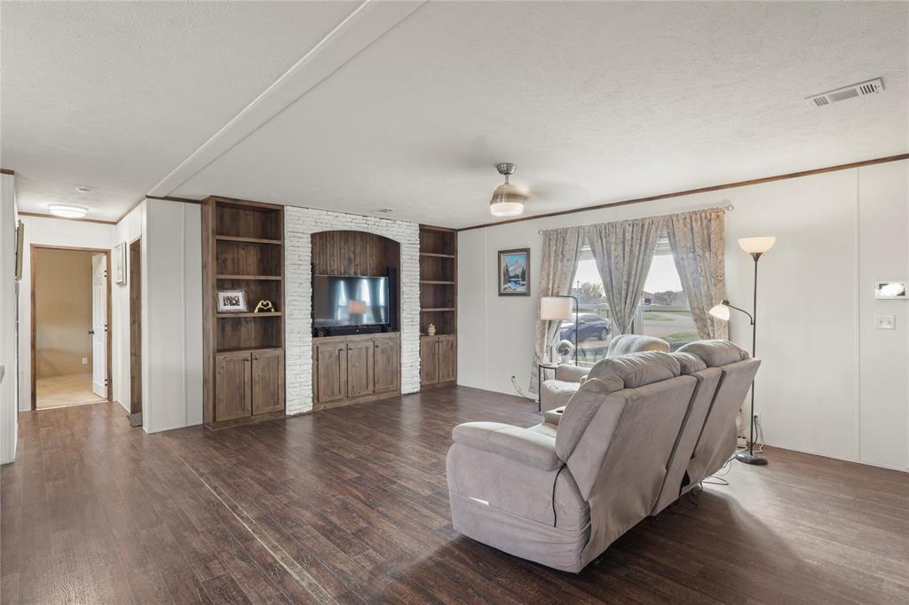 10240 Norrell Road Venus, TX 76084 - Photo 11 of 38 Living room featuring built in features, dark wood-style floors, and a textured ceiling