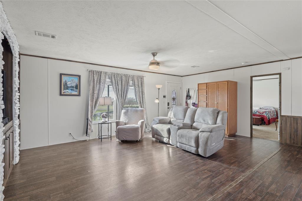 10240 Norrell Road Venus, TX 76084 - Photo 12 of 38 Living area with dark wood finished floors, a ceiling fan, a decorative wall, and a textured ceiling