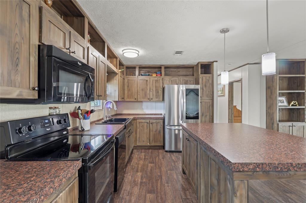10240 Norrell Road Venus, TX 76084 - Photo 15 of 38 Kitchen featuring black appliances, dark countertops, open shelves, dark wood-style flooring, and a textured ceiling