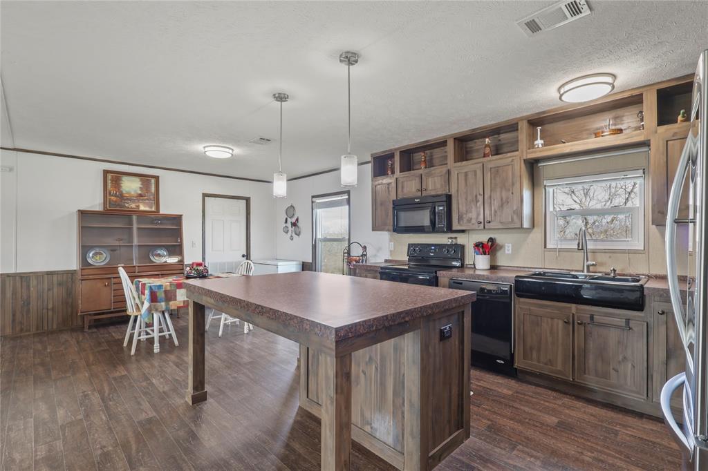 10240 Norrell Road Venus, TX 76084 - Photo 16 of 38 Kitchen with open shelves, dark countertops, black appliances, decorative light fixtures, and a kitchen island