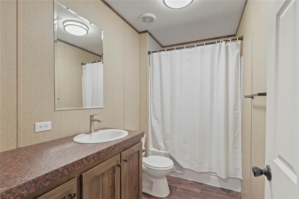 10240 Norrell Road Venus, TX 76084 - Photo 29 of 38 Full bath with a textured ceiling, vanity, dark wood-type flooring, shower / bath combo, and ornamental molding