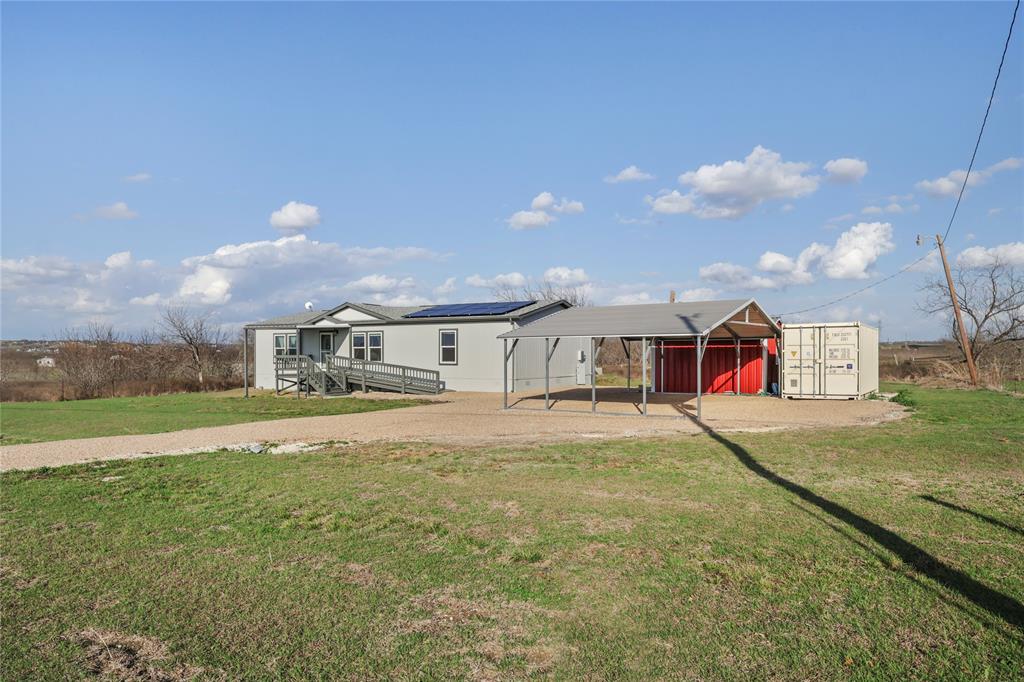 10240 Norrell Road Venus, TX 76084 - Photo 5 of 38 View of front of house with a detached carport, solar panels, a front yard, driveway, and a storage shed