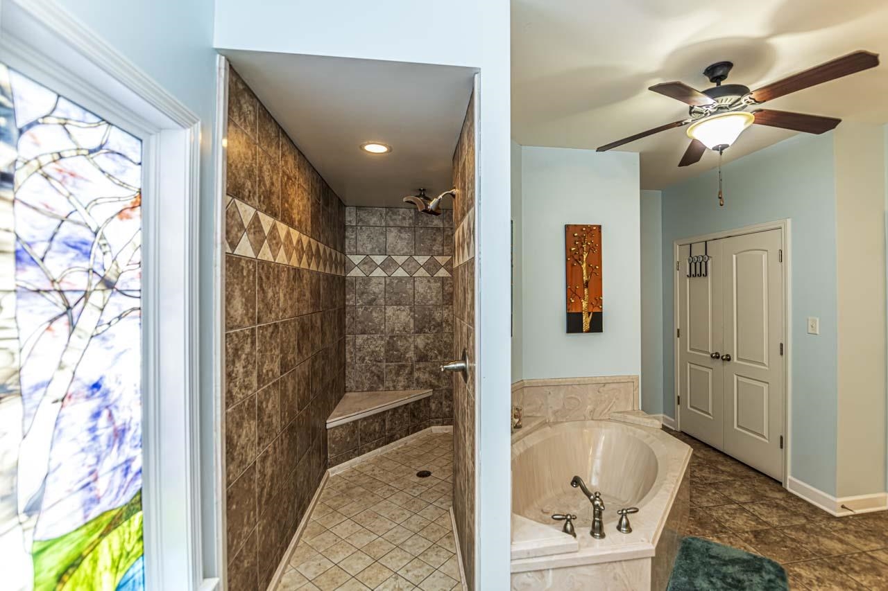 177 Leta Loop Brighton, TN 38011 - Photo 17 of 37 Bathroom with independent shower and bath, ceiling fan, and tile floors. Stained glass in primary bath will not stay.