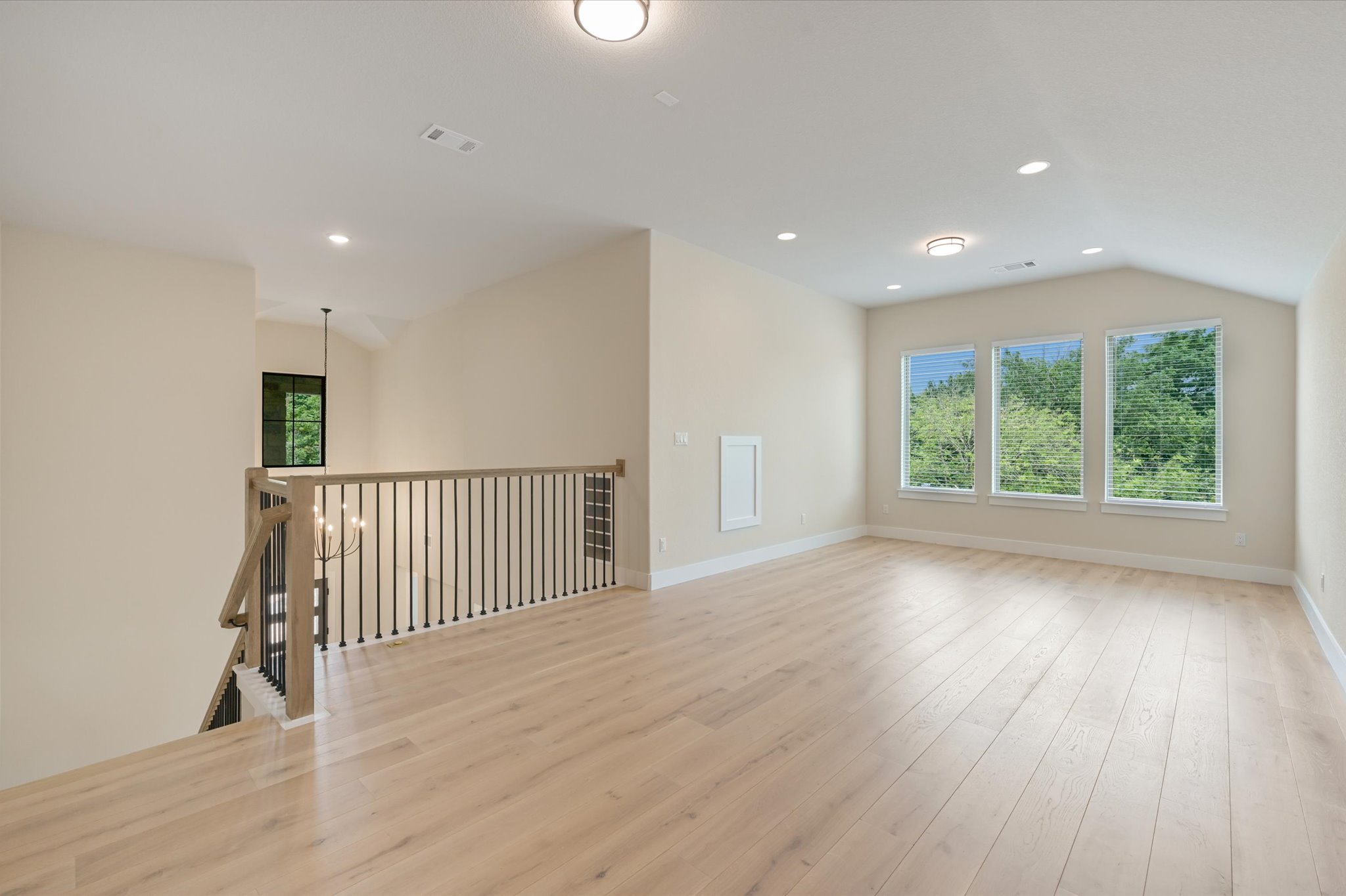 913 Presa Arriba Road Austin, TX 78733 - Photo 14 of 30 A generous loft space offers a peaceful escape, naturally illuminated by three windows overlooking lush greenery.