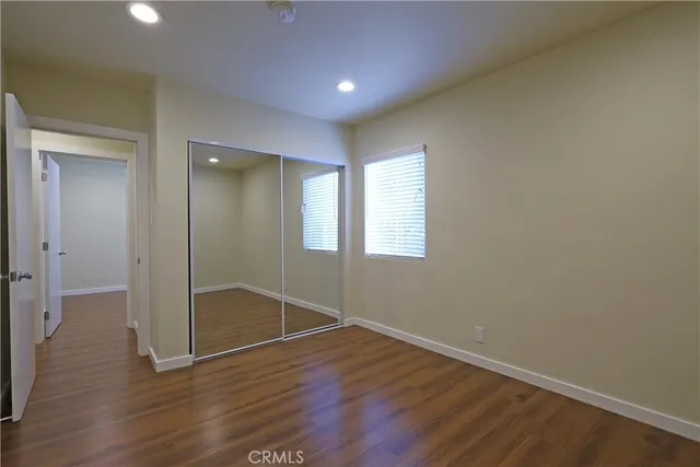an empty room with wooden floor & windows