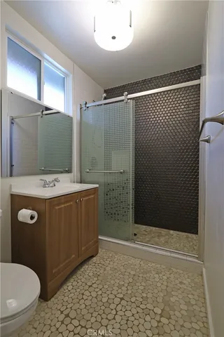 a bathroom with a granite countertop sink a toilet a mirror and shower