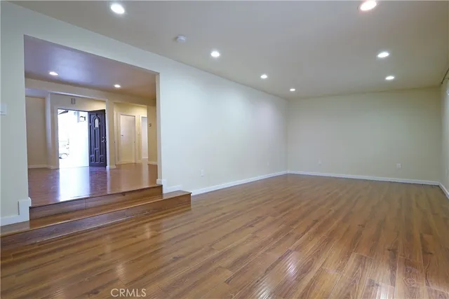 a view of an empty room with wooden floor and a bathroom