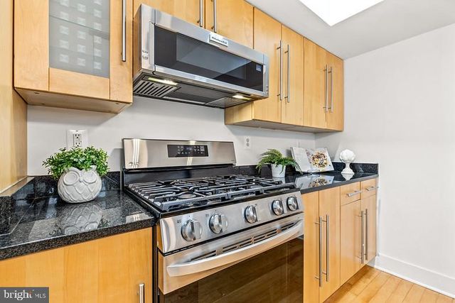 a kitchen with stainless steel appliances granite countertop a stove a microwave cabinets and a sink