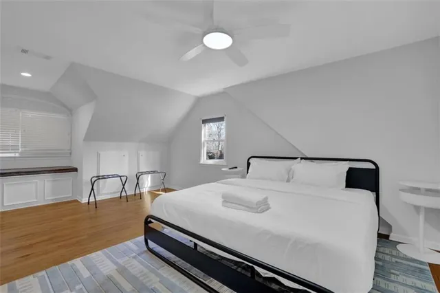 a bedroom with a bed and a dresser with wooden floor