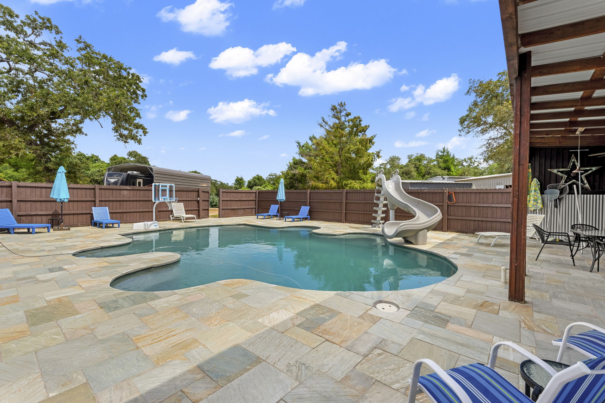 206 22 Hills Road Gause, TX 77857 - Photo 10 of 28 An inviting freeform swimming pool features a slide and is surrounded by extensive stone decking.