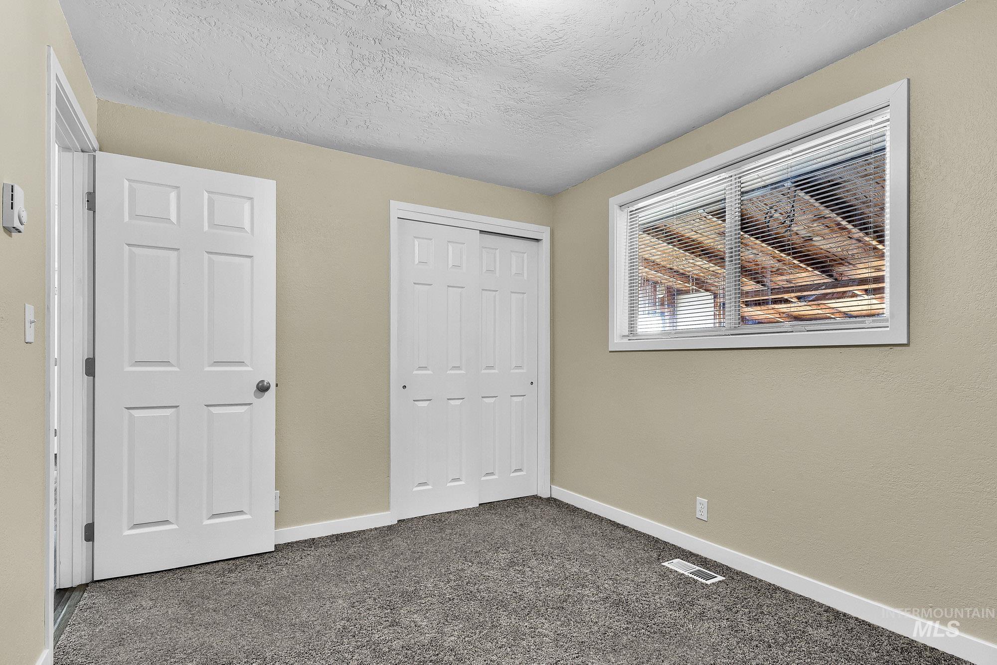 5755 Chuckwagon Road Nampa, ID 83686 - Photo 32 of 50 Neutral tone wall paint, textured ceiling, gray carpet flooring, white trim, and a window with blinds