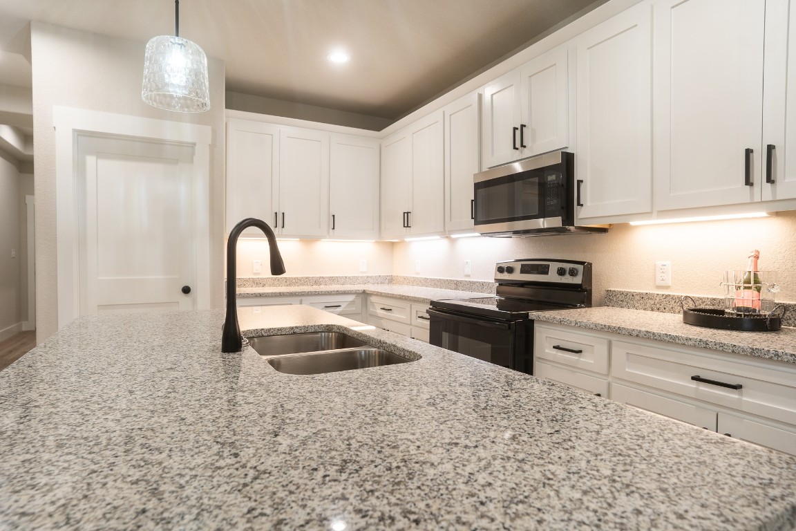 307 String Prairie Way Smithville, TX 78957 - Photo 13 of 34 Kitchen with electric range oven, stainless steel microwave, a sink, and white cabinets