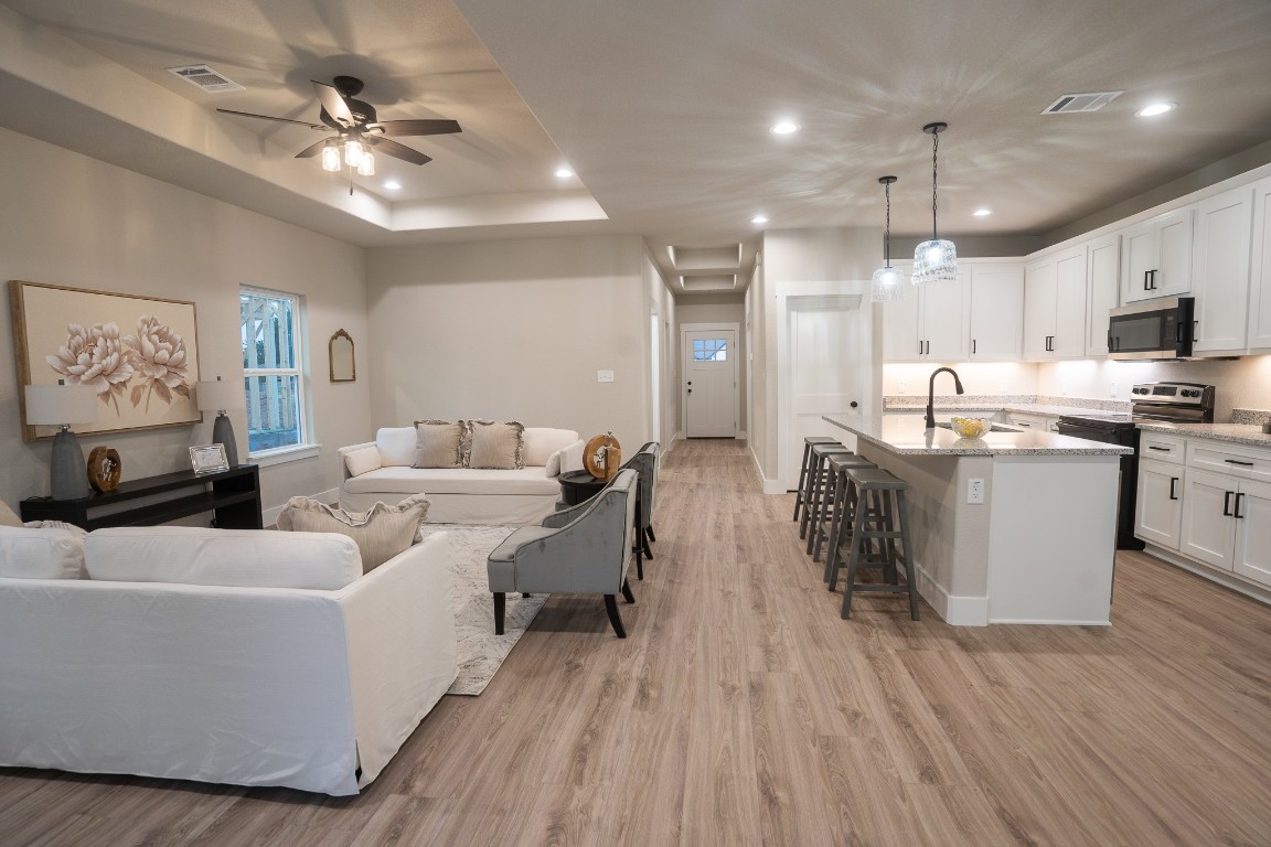 307 String Prairie Way Smithville, TX 78957 - Photo 17 of 34 Living area with light wood-style floors, ceiling fan, recessed lighting, and a raised ceiling