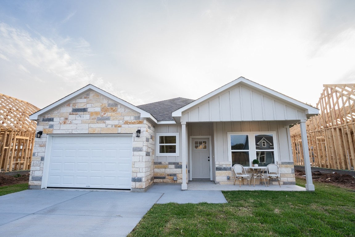 307 String Prairie Way Smithville, TX 78957 - Photo 2 of 34 View of front of house with stone siding, driveway, an attached garage, a shingled roof, and board and batten siding