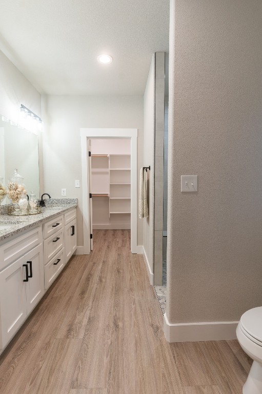 307 String Prairie Way Smithville, TX 78957 - Photo 24 of 34 Bathroom with wood finished floors, vanity, toilet, baseboards, and recessed lighting