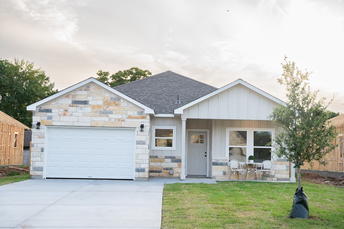 307 String Prairie Way Smithville, TX 78957 - Photo 4 of 34 View of front facade with roof with shingles, concrete driveway, stone siding, a garage, and a front yard