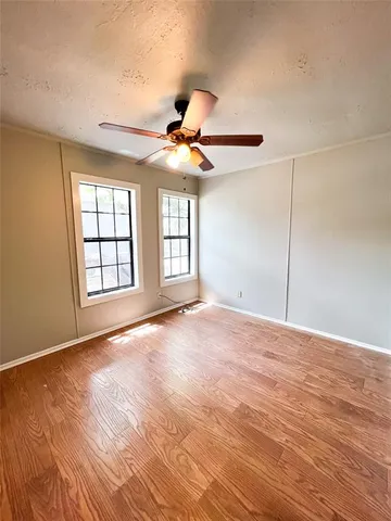 a view of an empty room with window and chandelier fan