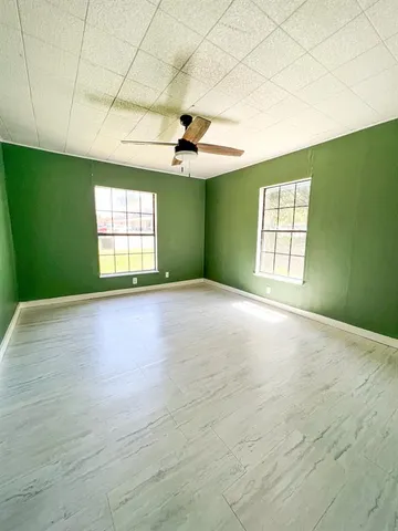 an empty room with windows and ceiling fan