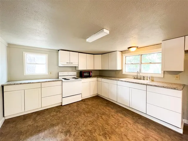 a large white cabinets with kitchen island sink and a window