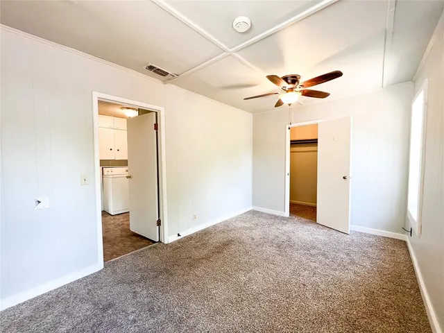 an empty room with closet and a ceiling fan