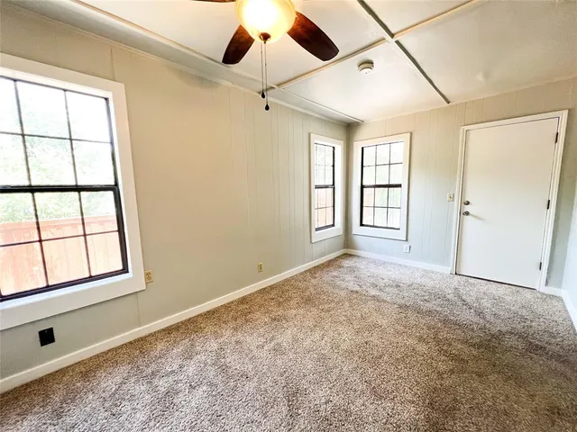 an empty room with windows and ceiling fan
