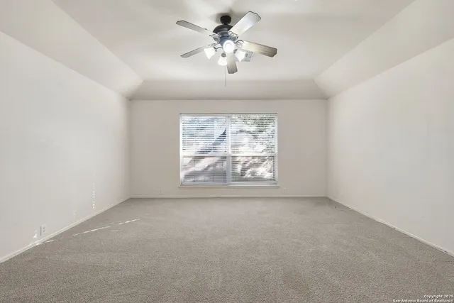 an empty room with windows and chandelier fan