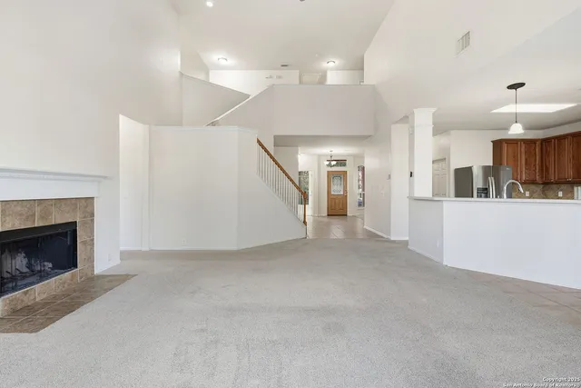 a view of a kitchen and an empty room with a fireplace
