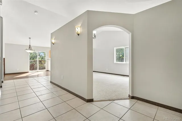 a view of a livingroom with wooden floor and a refrigerator in a kitchen