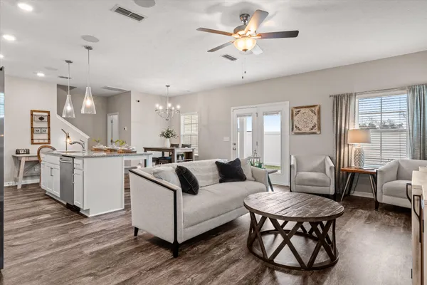 a living room with furniture kitchen view and a wooden floor