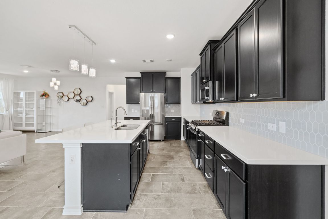 116 Thurman Holt Road Hutto, TX 78634 - Photo 33 of 35 Kitchen featuring dark cabinets, stainless steel appliances, backsplash, open floor plan, and recessed lighting
