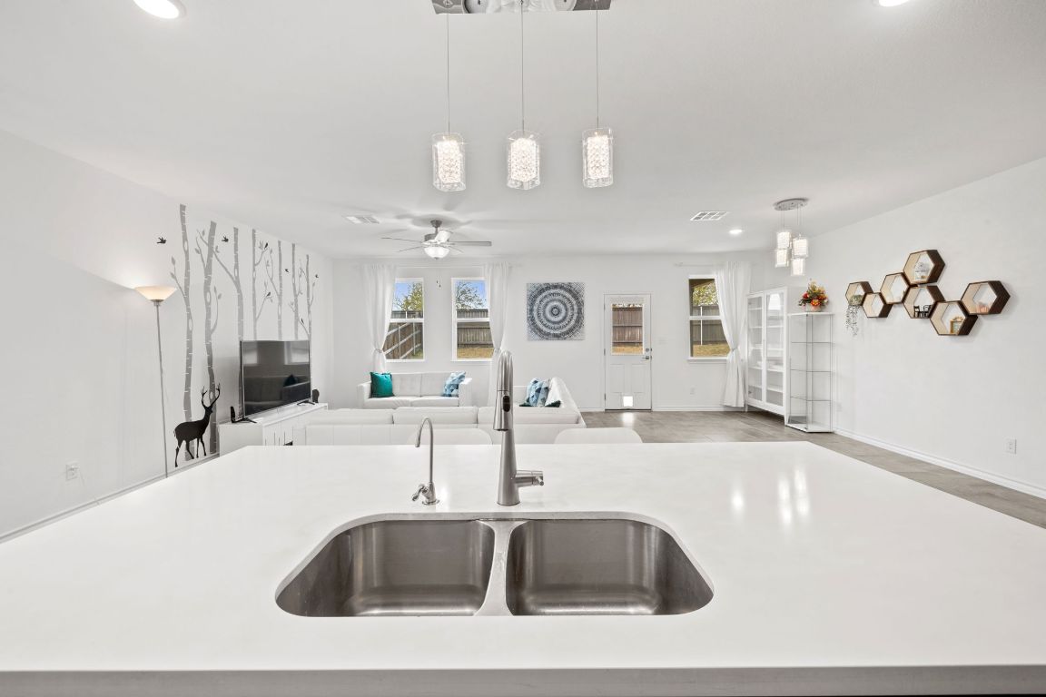 116 Thurman Holt Road Hutto, TX 78634 - Photo 34 of 35 Kitchen with an island with sink, open floor plan, recessed lighting, pendant lighting, and light stone counters