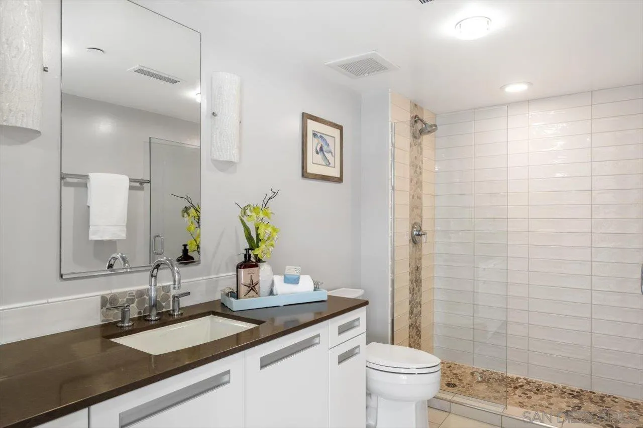 215 2nd Street, Unit 104 Encinitas, CA 92024 - Photo 20 of 22 a bathroom with a granite countertop sink a toilet and a mirror