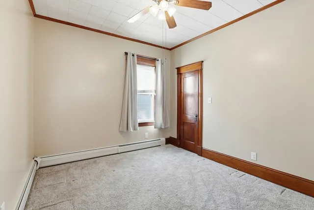 an empty room with a chandelier fan and windows