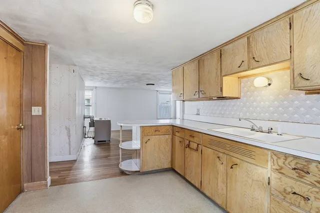 a kitchen with a sink dishwasher a stove and white cabinets with wooden floor