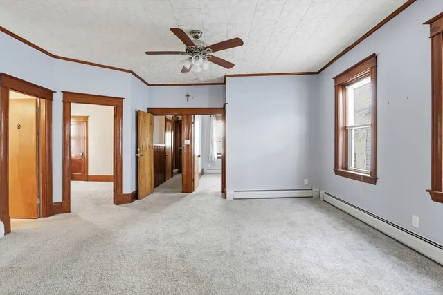 an empty room with chandelier fan and windows
