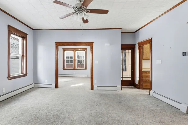 an empty room with chandelier fan and windows