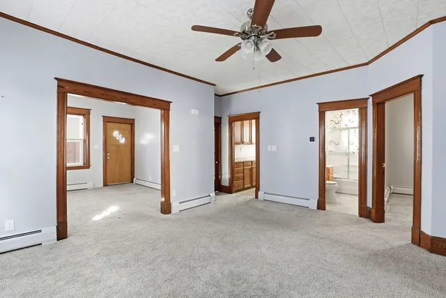 an empty room that has a chandelier fan and a large window