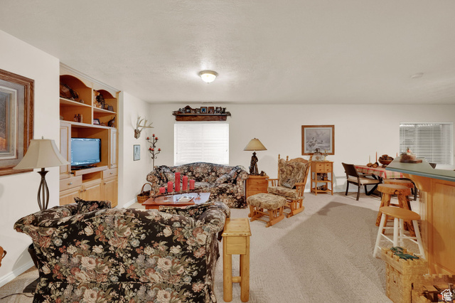 7740 Keswick Road Sandy, UT 84093 - Photo 45 of 74 Spacious interior featuring a built-in entertainment center with shelving, recessed lighting, and a breakfast bar with a solid surface countertop